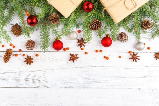 Подарунки на Новий рік, загорнуті в ремісничий папір поблизу ялинових гілок і шишок на білому дерев'яному фоні, вид зверху копія
 - Фото, зображення