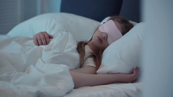 Selektiver Fokus der jungen Frau mit Schlafmaske, die im Bett ruht - Filmmaterial, Video