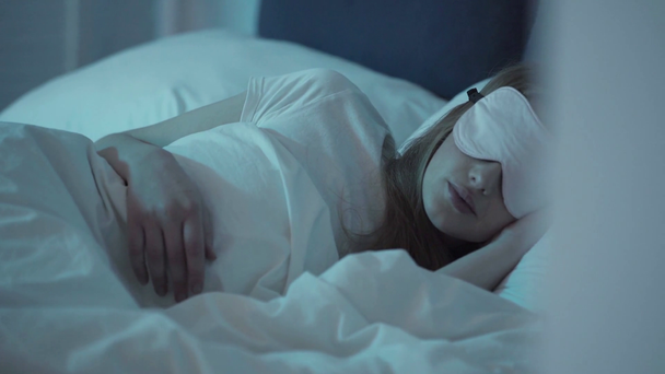 Selective focus of young woman with sleep mask on eyes sleeping at night  - Video