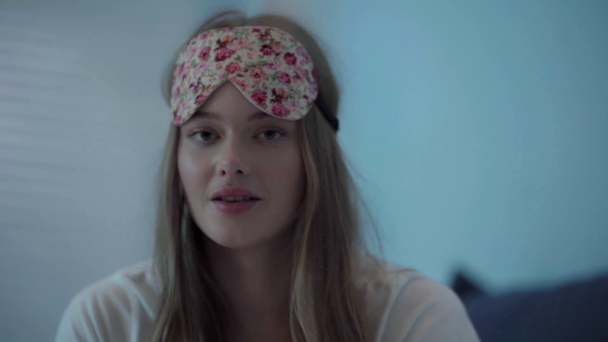 Young woman with sleep mask on head looking at camera - Materiał filmowy, wideo