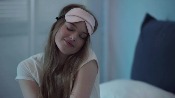 Mujer joven con la máscara de sueño rosa tocando la cara - Imágenes, Vídeo