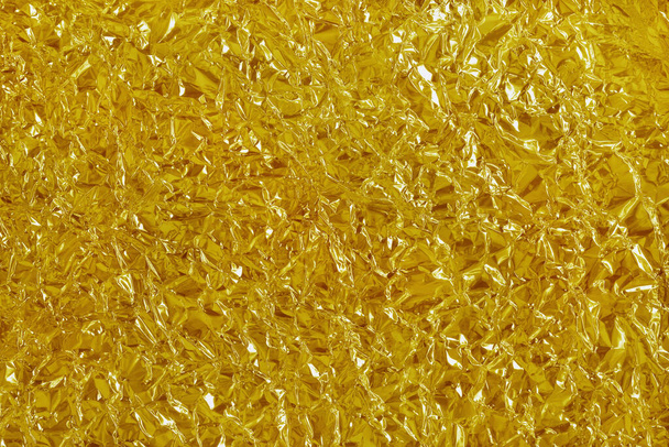 Altın folyo yaprağının parlak dokusu, arkaplan ve tasarım çalışmaları için soyut sarı ambalaj kağıdı. - Fotoğraf, Görsel