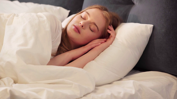 Jonge vrouw slaapt 's morgens in bed - Video