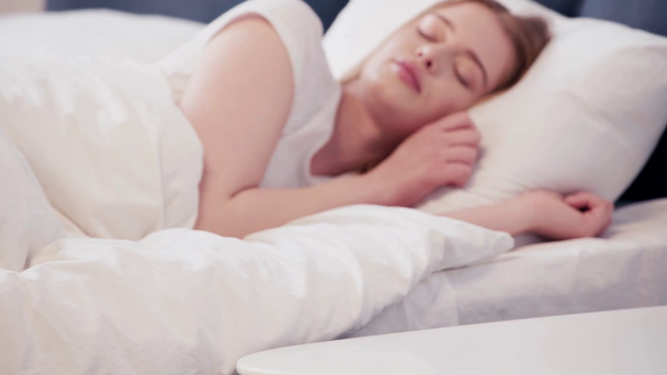 目覚まし時計を投げる睡眠女性の選択的な焦点  - 映像、動画