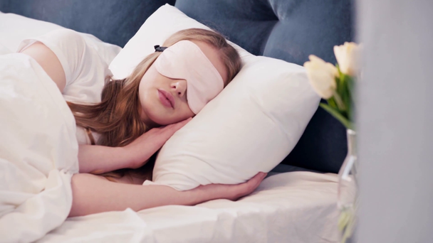 Młoda kobieta leżąca rano w masce snu na oczach - Materiał filmowy, wideo