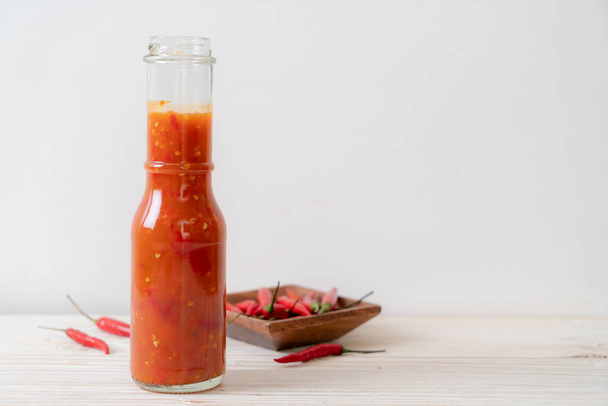 chilli or chilli sauce in bottle and jar on wwod background - Фото, изображение