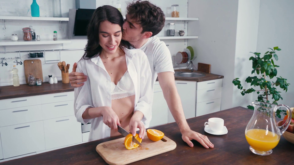 Чоловік прикриває очі і цілує дівчину в бюстгальтері і сорочці, вирізаючи апельсин
  - Кадри, відео