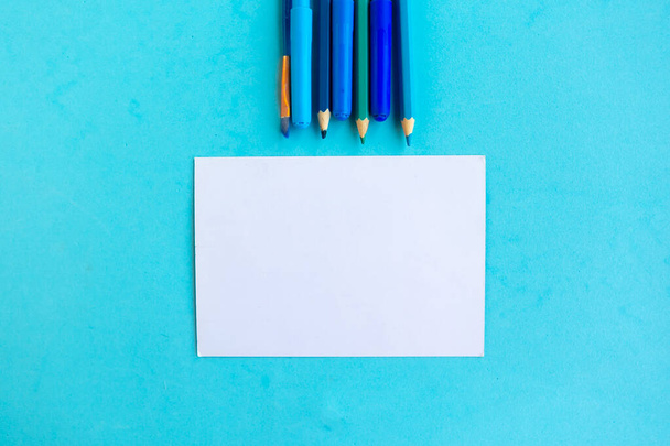 Lápices de color y maqueta blanca en blanco sobre fondo azul, vuelta al concepto de la escuela - Foto, Imagen