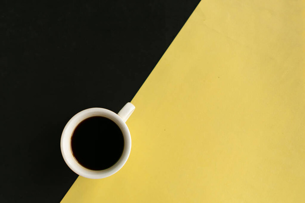 Coffee cup on geometric yellow and black background, top view, copy space for the text, minimal concept - 写真・画像