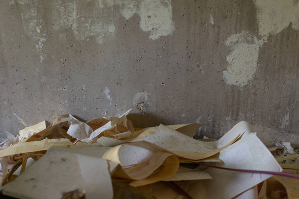 Uma pilha de papel de parede rasgado em um fundo de uma parede de concreto Reparar remoção de papel de parede antigo pergament papel do vintage - Foto, Imagem
