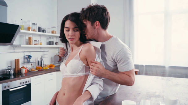 Hombre quitándose la camisa y besando sexy novia en la cocina  - Imágenes, Vídeo