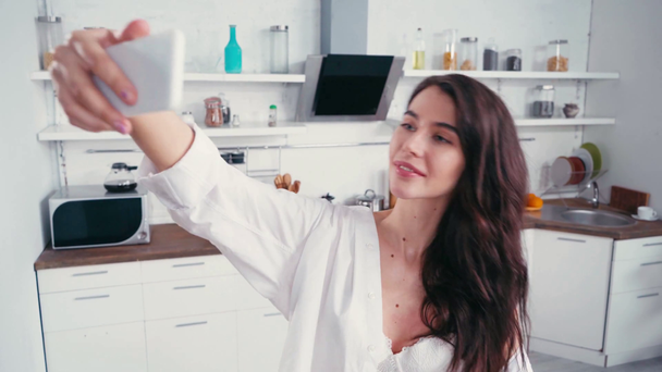 Σέξι γυναίκα με πουκάμισο που βγάζει σέλφι στην κουζίνα  - Πλάνα, βίντεο