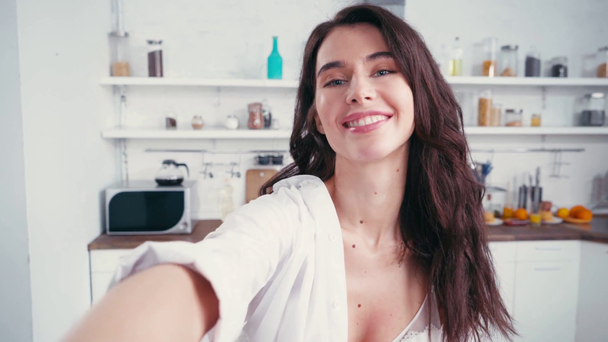 Сексуальная женщина в лифчике и рубашке смотрит в камеру на кухне  - Кадры, видео