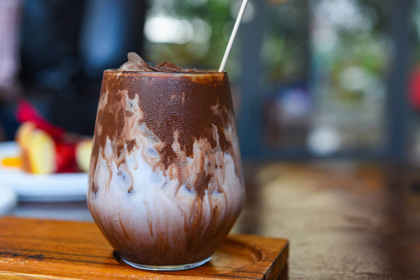 napój kakaowy i czekolada / smaczny napój mleczny z lodem kakaowym w szklance na tle drewna  - Zdjęcie, obraz