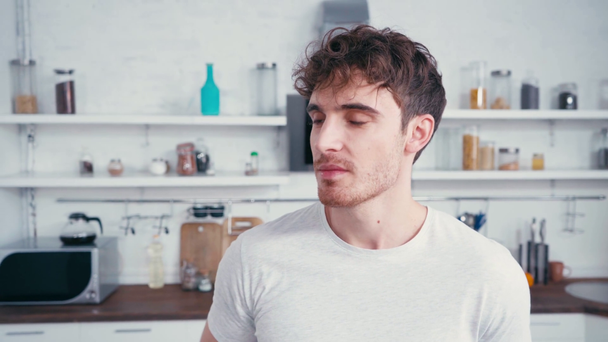 Junger Mann trinkt Orangensaft in Küche - Filmmaterial, Video