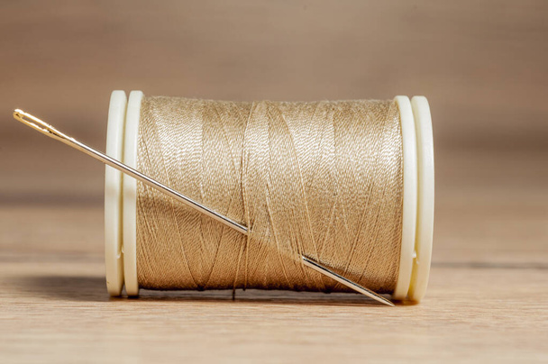A closeup shot of a roll of brown thread with a needle - Foto, Bild
