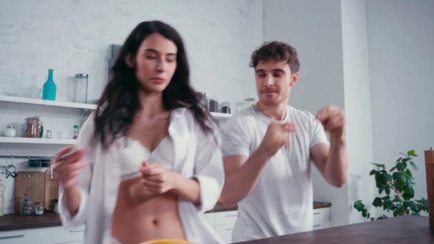 Homem dançando perto de mulher sexy ao lado da mesa da cozinha  - Filmagem, Vídeo