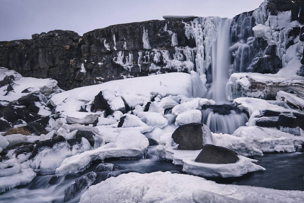 A closeup shot of an icy waterfall with some snow around in Oxarafos Iceland - Foto, imagen