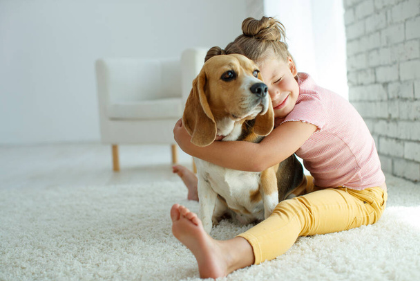 Kind mit Hund. Ein kleines Mädchen spielt zu Hause mit einem Hund. Kind und Tier. - Foto, Bild