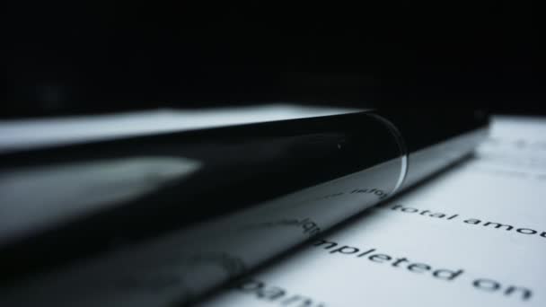 Detailní černé pero ležící na papírové smlouvě. Znak makra s textem přísně tajným - Záběry, video
