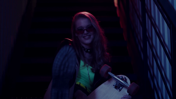 žena ve slunečních brýlích drží brusle, zatímco sedí a směje se na schodech - Záběry, video