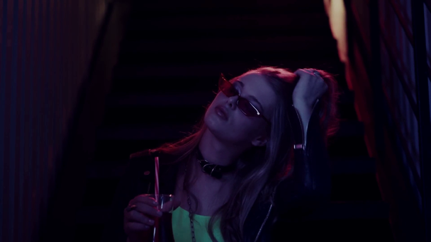 junge Frau mit Sonnenbrille trinkt Cocktail und sitzt auf der Treppe - Filmmaterial, Video