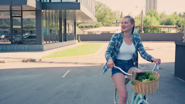 young woman riding bicycle near buildings outside  - Felvétel, videó