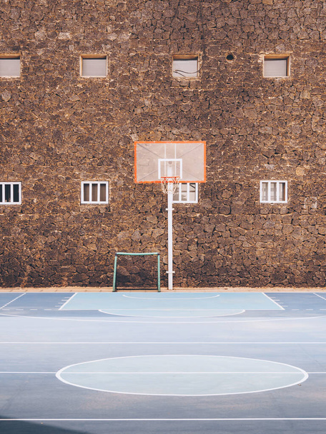 A vertical shot of an empty basketball pitch with a brown building on the background - Photo, Image