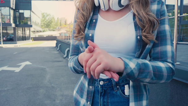 vista recortada de la mujer con auriculares inalámbricos que aplican desinfectante en las manos  - Metraje, vídeo