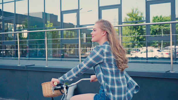giovane donna in bicicletta vicino edificio moderno al di fuori  - Filmati, video