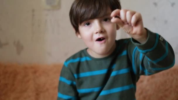小さなハンサムな男の子は、彼のミルクの歯が落ちたことを示しています。子供の歯を変えるという概念 - 映像、動画