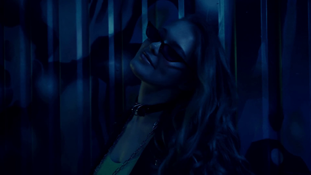 женщина в солнцезащитных очках ходит и смотрит на камеру рядом со стеной с граффити  - Кадры, видео