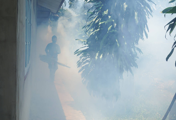 Humanos desfocados trabalham na neblina de mosquitos para prevenir a propagação da dengue na comunidade.Prevenção de epidemias e conceitos de saúde. - Foto, Imagem