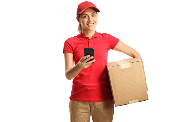 Delivery woman holding a cardboard box and a mobile phone isolated on white background  - Fotografie, Obrázek
