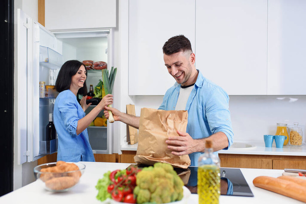Young stylish couple unpacking together fresh products from market in cozy kitchen. - Foto, Imagen
