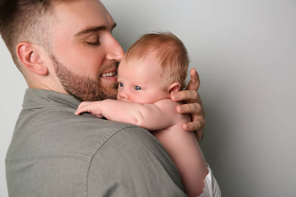 Father with his newborn son on light grey background, closeup - Photo, image