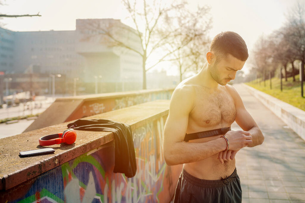 Mladý sportovní muž využívající fitness hodinky - bělošský běžec připravující sledovací výkon se sportovním twatchem - sport, fitness, technologický koncept - Fotografie, Obrázek