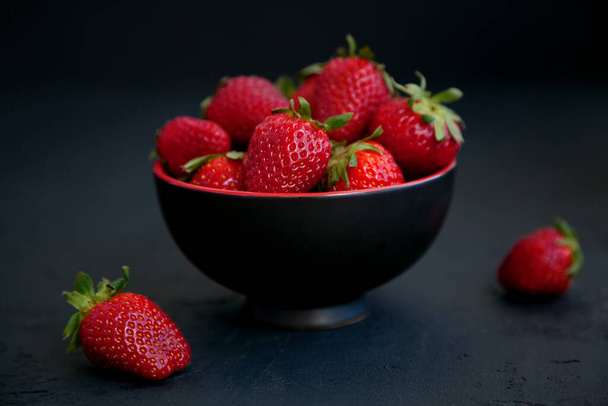 Ripe red fresh strawberries in a bowl on a black background - Фото, зображення