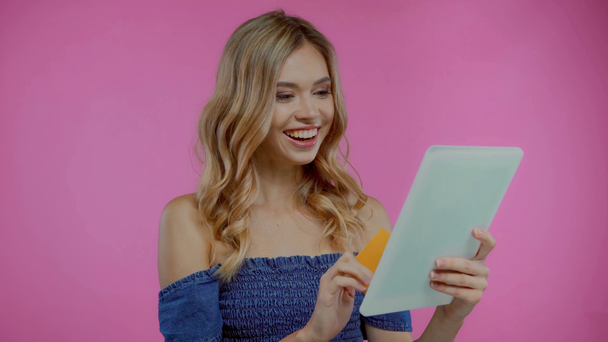 Blonde Frau mit Kreditkarte und digitalem Tablet isoliert auf lila - Filmmaterial, Video