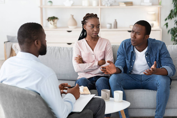 Huwelijkstherapie sessie. Zwart echtpaar spreekt met familie counselor over relatieproblemen - Foto, afbeelding