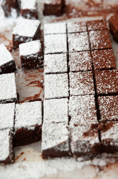 Deliciosos chocolates crus caseiros cortados em formas quadradas polvilhadas com açúcar em pó. Celebração do Dia dos Namorados. Tiro vertical. Close-up. - Foto, Imagem