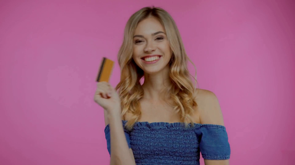 Nadšené blondýny žena ukazující kreditní kartu izolované na fialové - Záběry, video