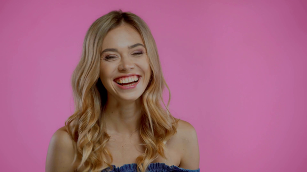 Blondýny žena se směje a dívá se na kameru izolované na fialové - Záběry, video