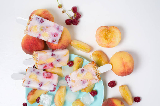 fresh summer ice cream on a stick with peach and raspberry berries . on light background. - Fotoğraf, Görsel
