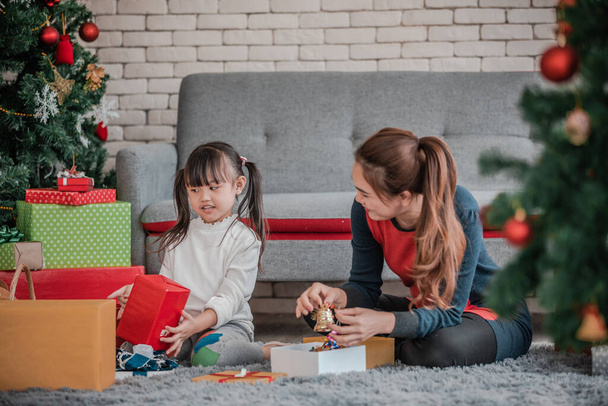 Portrait of happy family with Christmas gifts and having fun withdecorating Christmas tree  on floor at home. - Photo, image