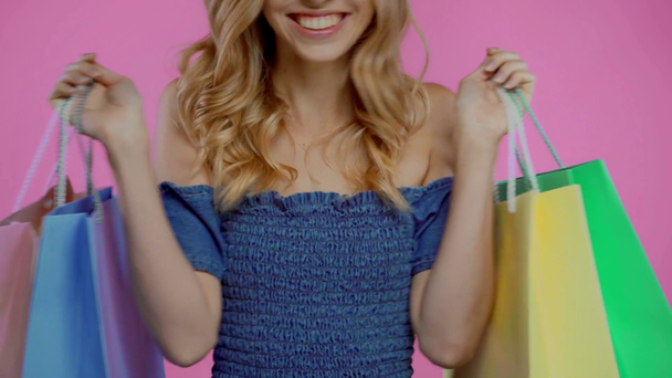 Cropped view of young woman dancing with shopping bags isolated on purple - Footage, Video