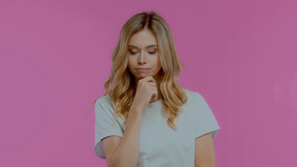 Niezadowolona blondynka pokazuje wzruszający gest odizolowany na fioletowym - Materiał filmowy, wideo