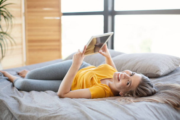 Menina bonita assistindo webinar ou filme no computador tablet em sua cama em casa - Foto, Imagem