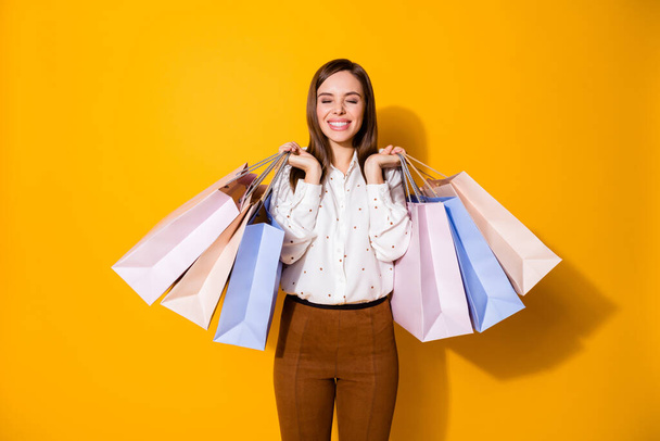 Portrait of her she nice-looking attractive lovely pretty fashionable glad cheerful cheery brown-haired girl carrying new clothes isolated bright vivid shine vibrant yellow color background - Foto, Imagen