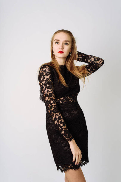 Beautiful woman in a black lace dress is standing in the studio on a white background. - Foto, Imagem
